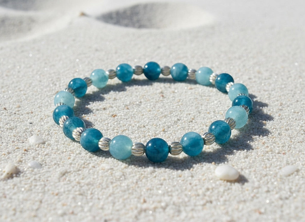 Bailey’s Bits & Baubles ocean blue Larimar and sterling silver pumpkin bead bracelet resting on beach sand.