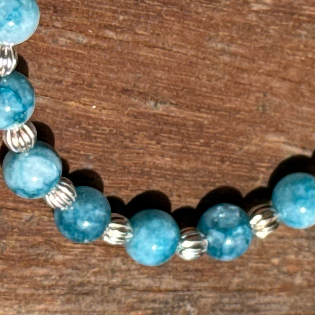 Bailey’s Bits & Baubles ocean-blue Larimar and sterling silver pumpkin bead bracelet on a wooden surface.