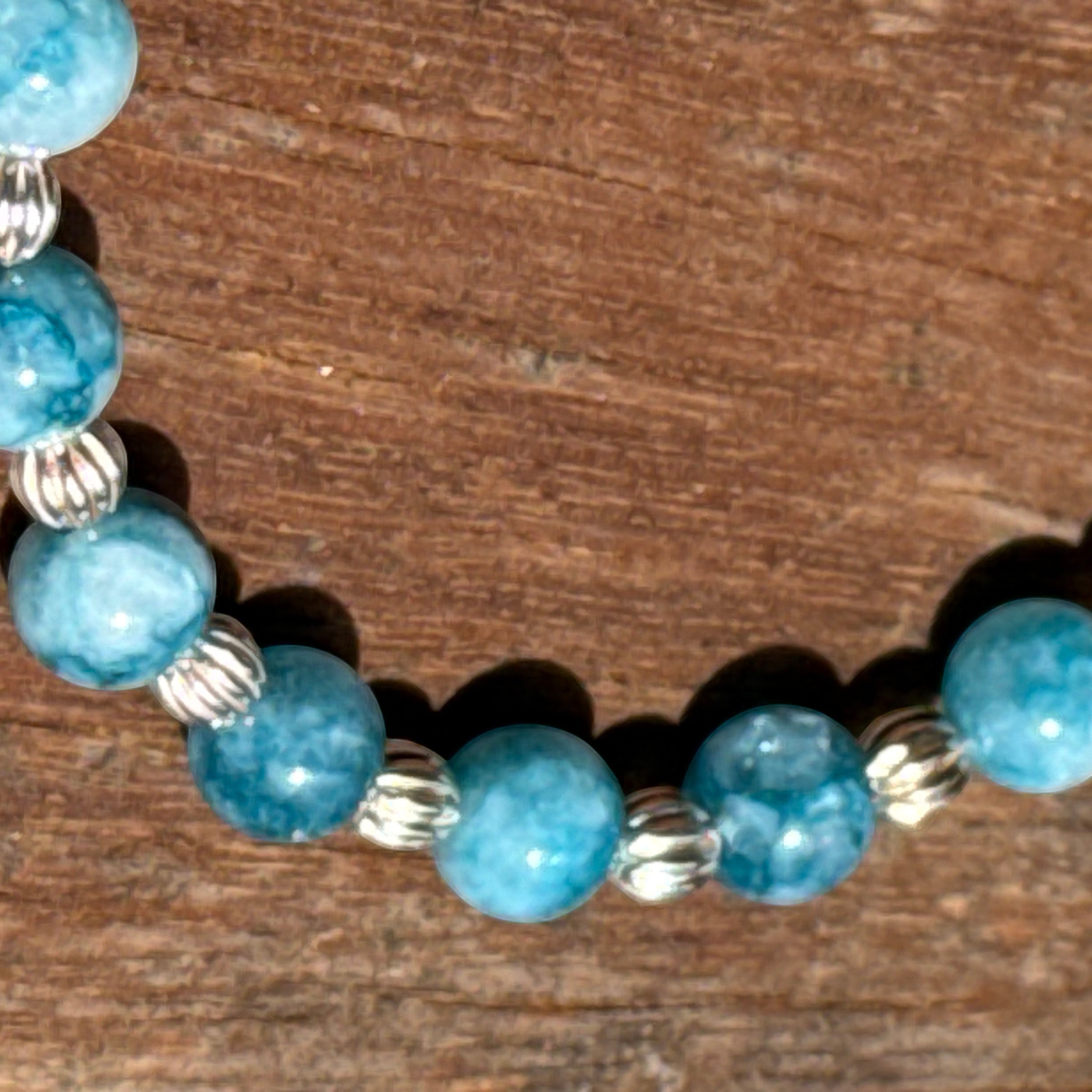 Bailey’s Bits & Baubles ocean-blue Larimar and sterling silver pumpkin bead bracelet on a wooden surface.