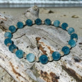 Bailey’s Bits & Baubles ocean blue Larimar and sterling silver pumpkin bead bracelet resting on weathered driftwood.