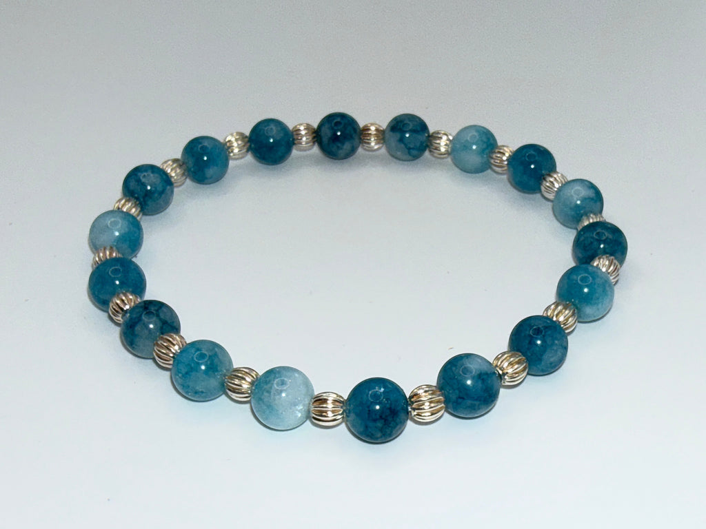 Bailey’s Bits & Baubles ocean blue Larimar and sterling silver pumpkin bead bracelet resting on white background.