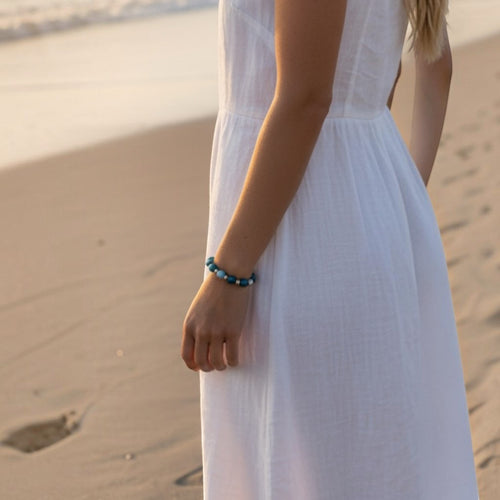 Bailey’s Bits & Baubles ocean blue Larimar and sterling silver bead bracelet worn on a beach at sunset.